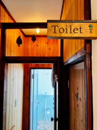a door to a toilet sign in a room at Guesthouse Azumaya in Matsumoto