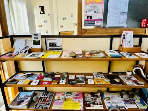 a display of books and magazines on a shelf at Guesthouse Azumaya in Matsumoto