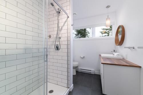 a white bathroom with a shower and a toilet at Les Chalets du Massif de Charlevoix in Petite-Rivière-Saint-François