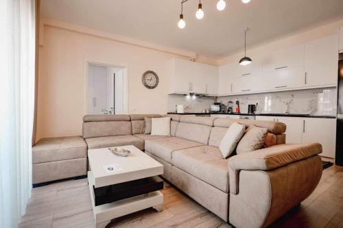 a living room with a large couch and a kitchen at Ari's Apartment Sarande in Sarandë