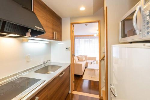 a small kitchen with a sink and a refrigerator at Tsutenkaku Royal House - Self Check-In Only in Osaka