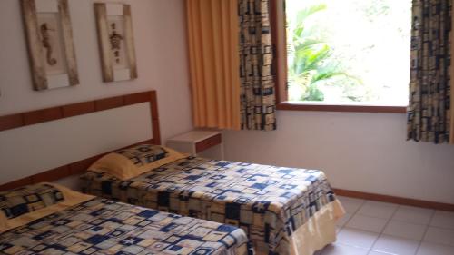 Cette chambre comprend deux lits et une fenêtre avec des rideaux. dans l'établissement Praia do Forte Estúdio, à Praia do Forte