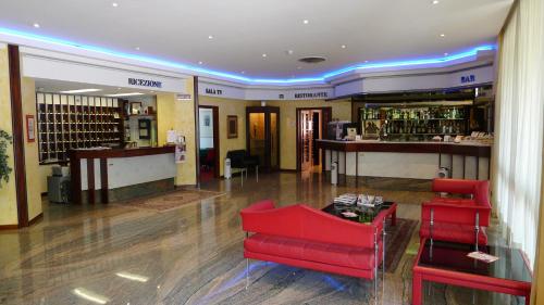 a lobby with a red chair and a bar at Hotel Grassetti in Corridonia