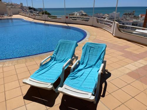アルブフェイラにあるOcean Balconyのスイミングプールの隣に座るビーチチェア2脚