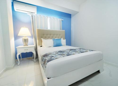 1 dormitorio con cama blanca y pared azul en Charming 2 bed 1 bath with Pool en Las Flores