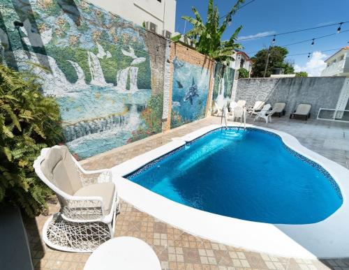 Las Flores的住宿－Captivating 2-1 with Ocean Views，一个带两把椅子和一张桌子的游泳池以及一面墙