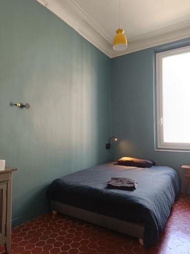 une chambre avec un lit avec un mur bleu dans l'établissement Chambre d'hôte 1 pers - Maison avec terrasse et jardin près de la Friche de la Belle de Mai, à Marseille