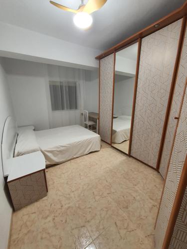 Habitación pequeña con cama y espejo. en Piso cerca playa Almeria en Almería