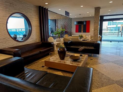 a lobby with leather couches and a mirror at Reymar Hotel Maceió in Maceió