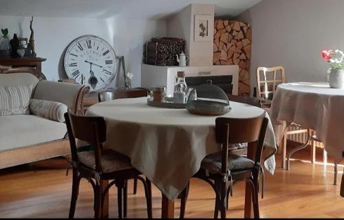 a living room with a table with chairs and a clock at Lo noú in Aosta