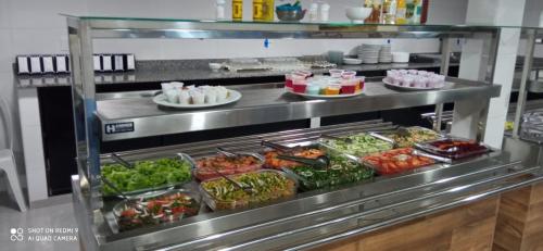 a buffet line in a restaurant with salads and food at Hotel Jardim Paraiba in Aparecida