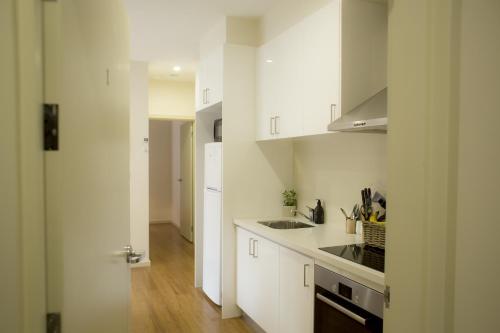 a white kitchen with a sink and a stove at The Town Apartments in Melbourne