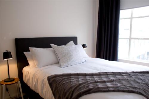 a bedroom with a bed with white pillows and a window at The Town Apartments in Melbourne