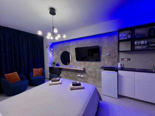 ein Schlafzimmer mit einem weißen Bett und eine Küche mit blauen Lichtern in der Unterkunft Fat Cow Apartment 01 in Larnaka
