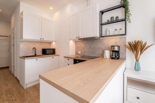 a kitchen with white cabinets and a wooden counter top at Flatbook Apartamenty - Mikoszewo Dom Amber Cottage in Nickelswalde