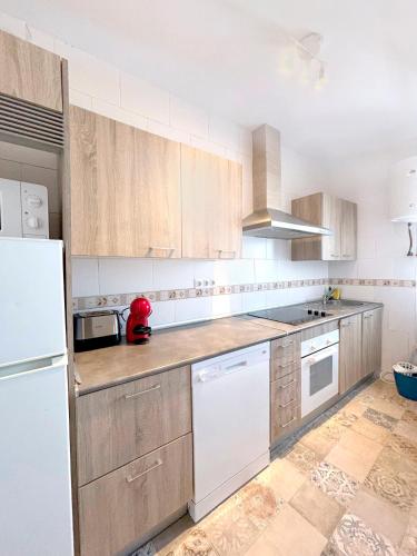 a kitchen with wooden cabinets and a white refrigerator at Gran Teatro Falla in Cádiz