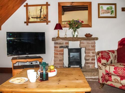sala de estar con mesa y chimenea en Millstone Cottage - Uk46676 en Highley