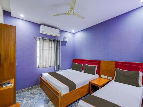 um quarto com 2 camas e uma parede roxa em Collection O elegant residency em Chennai