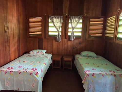 two beds in a room with wooden walls and windows at Chamisal Jungle Hotel in Lima