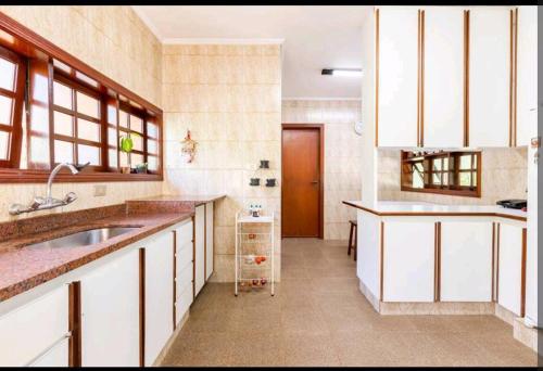 uma grande cozinha com armários brancos e um lavatório em Casa na Granja Viana - Cotia em Cotia