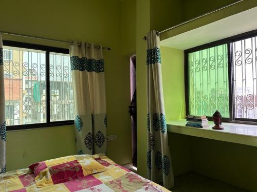 a bedroom with a bed and two windows at Amma’s Om stay in Patna