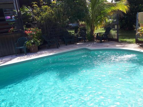 a swimming pool with blue water in a yard at GITE PEI LA VANILLE Duplex Bord de Nature in Sainte-Suzanne