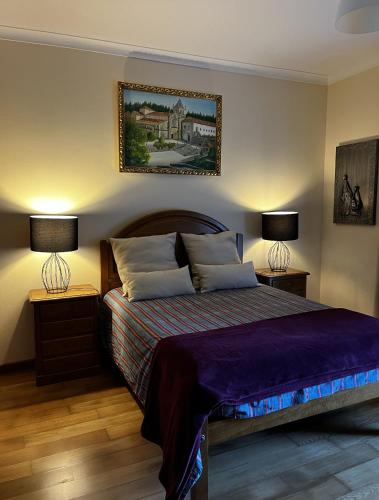 a bedroom with a bed with two lamps and a picture on the wall at Casa do Eirô in Resende