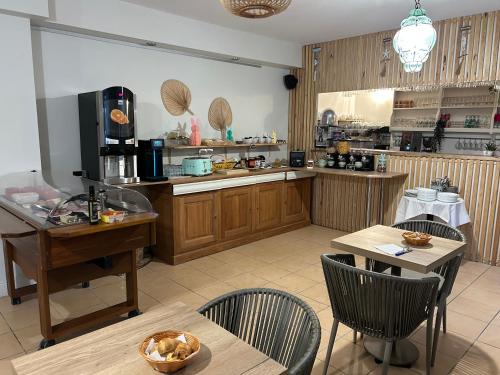 una cocina con armarios de madera, mesas y sillas en Logis Hotel De La Clape, en Narbonne-Plage