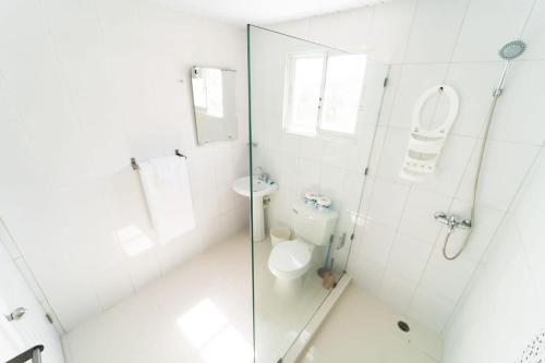 a white bathroom with a toilet and a glass shower at Breathtaking 3-2 with Ocean View in Las Flores