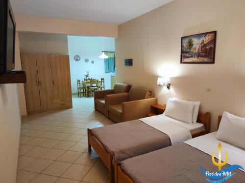 Habitación de hotel con 2 camas y sala de estar. en Poseidon Hotel Karystos en Karystos