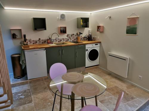 uma cozinha com uma mesa e uma máquina de lavar roupa em Gite La Maisonnette em Chancelade
