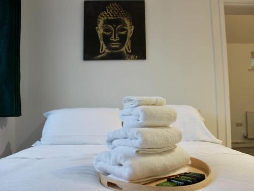 einen Stapel Handtücher auf einem Tablett auf einem Bett in der Unterkunft Modern Guest Lodge, Centrally Located, Free Parking, 8 Min to LGW Airport in Crawley