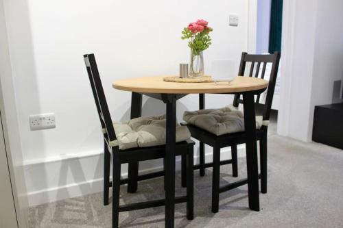 une table en bois avec deux chaises et un vase avec des fleurs dans l'établissement Modern Guest Lodge, Centrally Located, Free Parking, 8 Min to LGW Airport, à Crawley