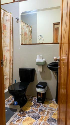 a bathroom with a black toilet and a sink at Suite de Asdruval in Puerto Baquerizo Moreno