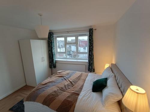 a bedroom with a large bed and a window at Spacious 3 bed flat opp Springfield park, Hackney. in London