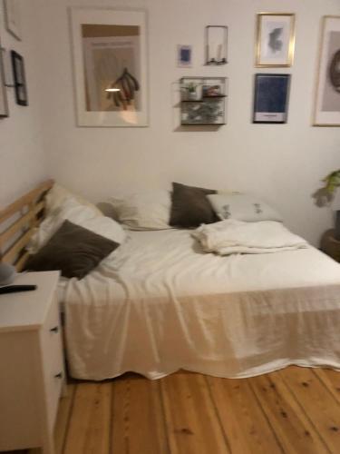 um quarto com uma cama com lençóis brancos e fotografias na parede em Sky view Perfect location Nightscape em Berlim