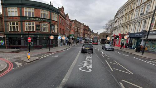 a city street with cars driving down the street at Wood studio flat in London