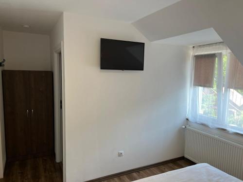a bedroom with a flat screen tv on a white wall at Pensiunea Mara Băile Botiza in Botiza