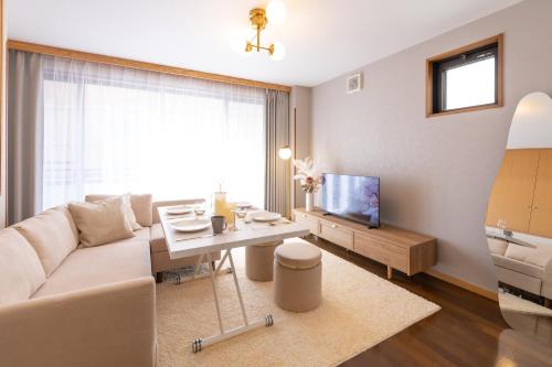 a living room with a white couch and a tv at Tsutenkaku Royal House - Self Check-In Only in Osaka