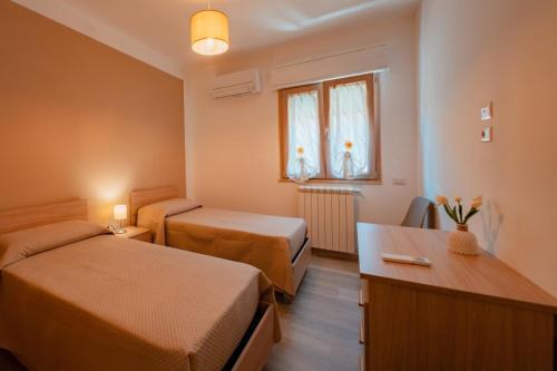 een kleine hotelkamer met 2 bedden en een bureau bij Guest House Cefalù in Cefalù