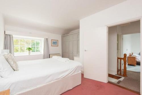 a white bedroom with a large bed and a window at Blue Cottage - 3 bedroom cottage in Feock in Feock