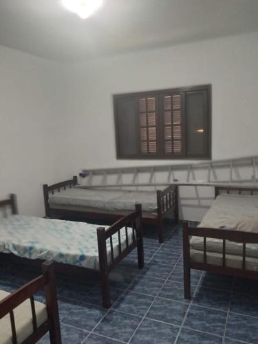 a room with four beds and a window at Casa Itanhaem in Itanhaém