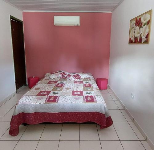 een slaapkamer met een bed met een rode muur bij Pousada Cachoeira do Campo in Aquidauana