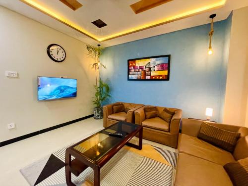 a living room with a couch and a clock on the wall at Own It Apartment Brown in Islamabad