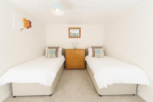 two beds in a room with white walls at Achloist Holiday Cottage in Drumbeg