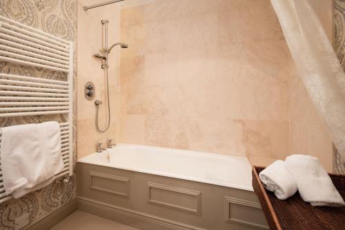 a bathroom with a tub and a shower with towels at Broadgate Farmhouse in West Woodburn