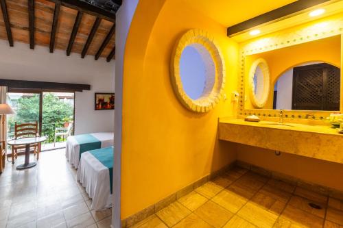 a bathroom with a yellow wall and a sink at Hacienda Buenaventura Hotel & Mexican Charm - All Inclusive in Puerto Vallarta