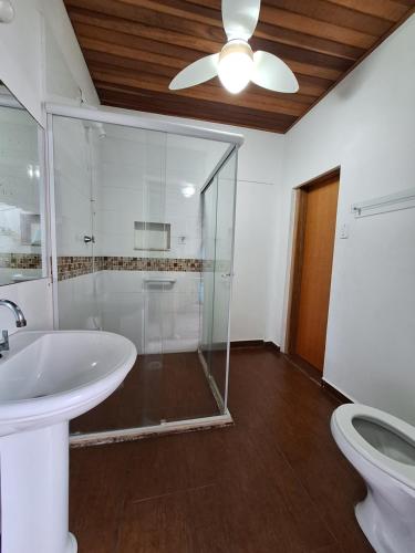 a bathroom with a glass shower and a sink at Suítes Pitangueiras in Guarujá