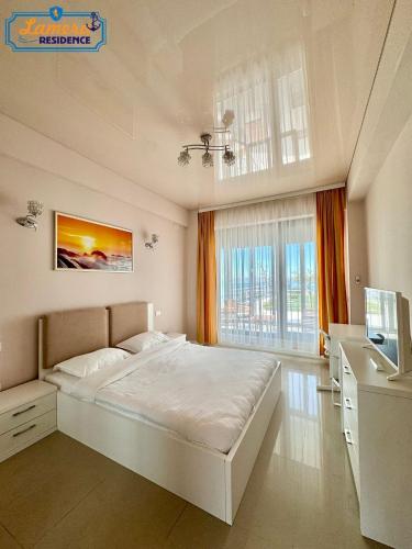a bedroom with a large white bed and a desk at Lamera Residence Mamaia - Apartamente cu 1-2-3 camere cu acces si vedere la lac in Mamaia