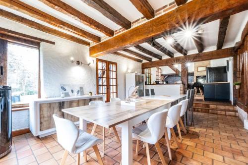 une cuisine avec une grande table en bois et des chaises blanches dans l'établissement Maison de famille en Sologne, à Yvoy-le-Marron